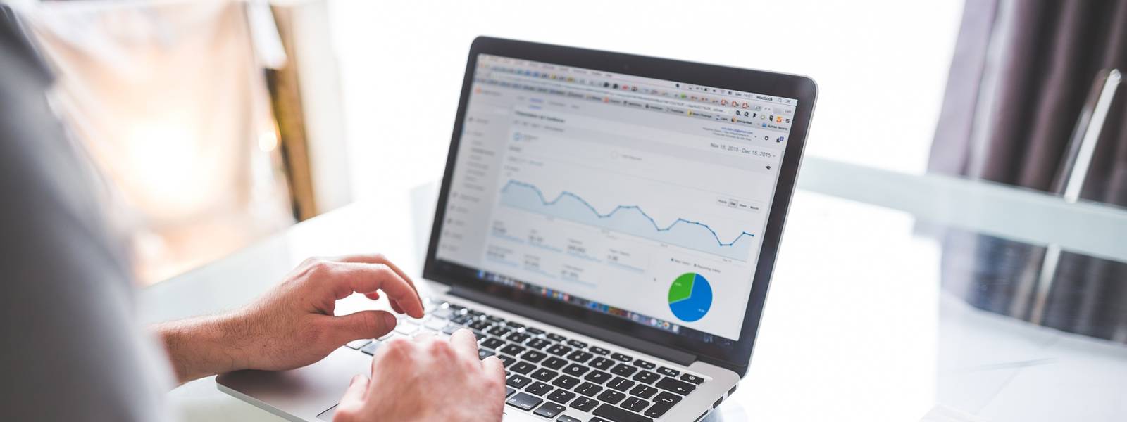 Person analysing data on a laptop with coffee and snacks on a table.