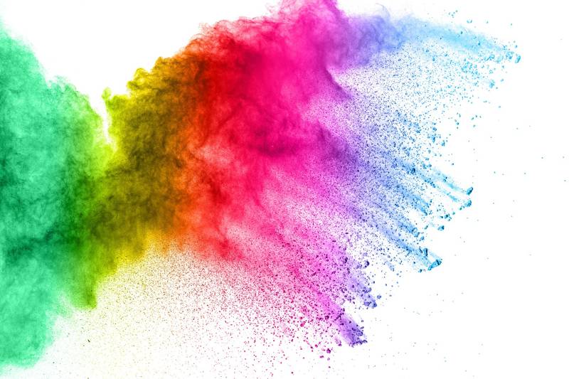 Vibrant powder explosion in green, yellow, red, and blue against a white background.