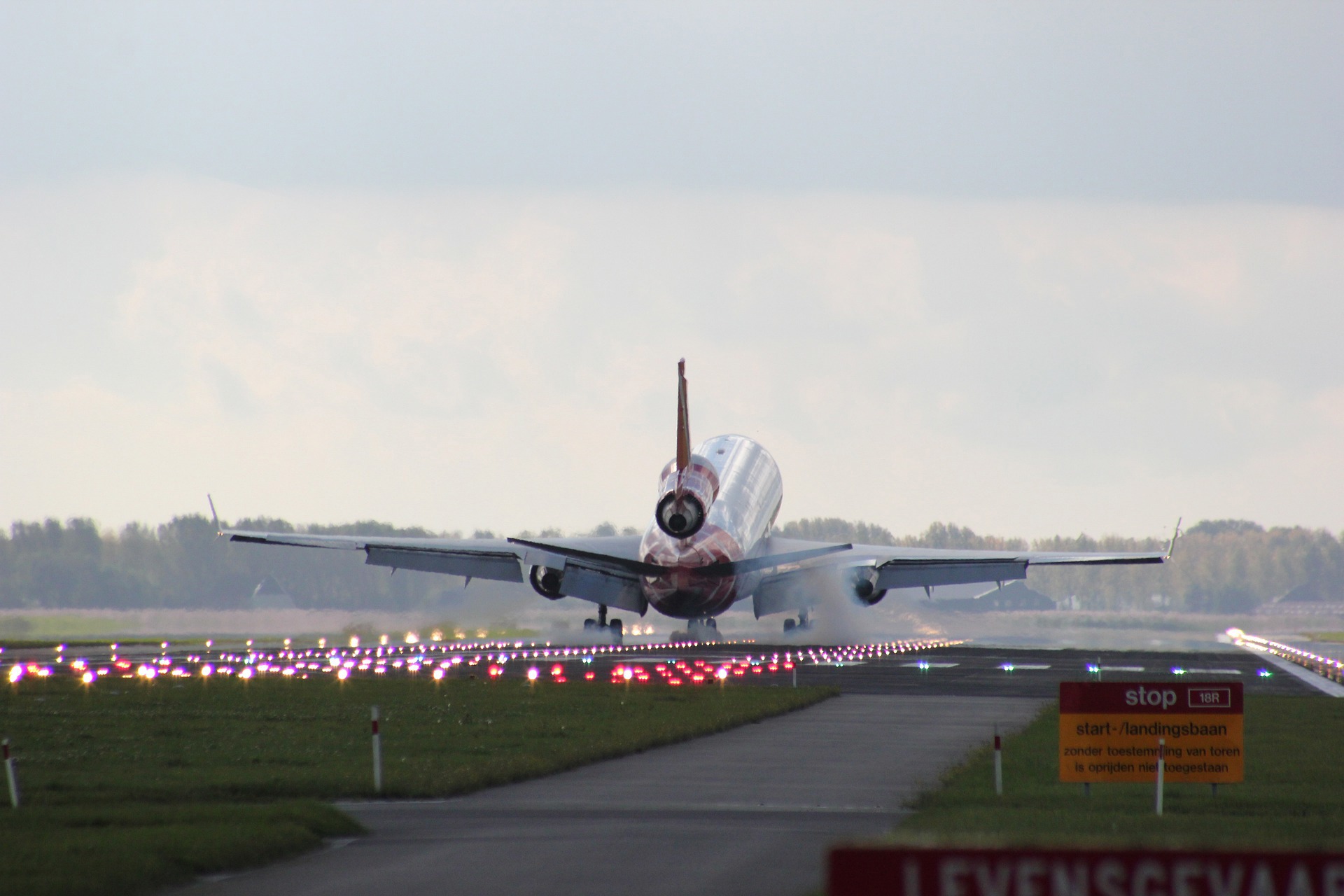 Commercial aircraft approaching runway, illuminated by landing lights.