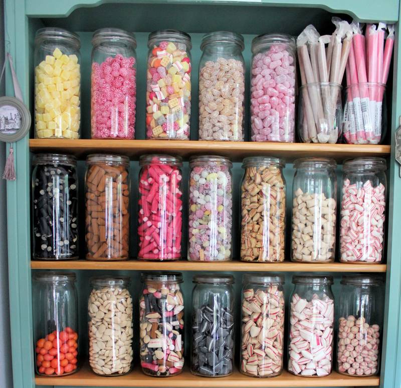 A colourful display of jars filled with various sweets on a wooden shelf.