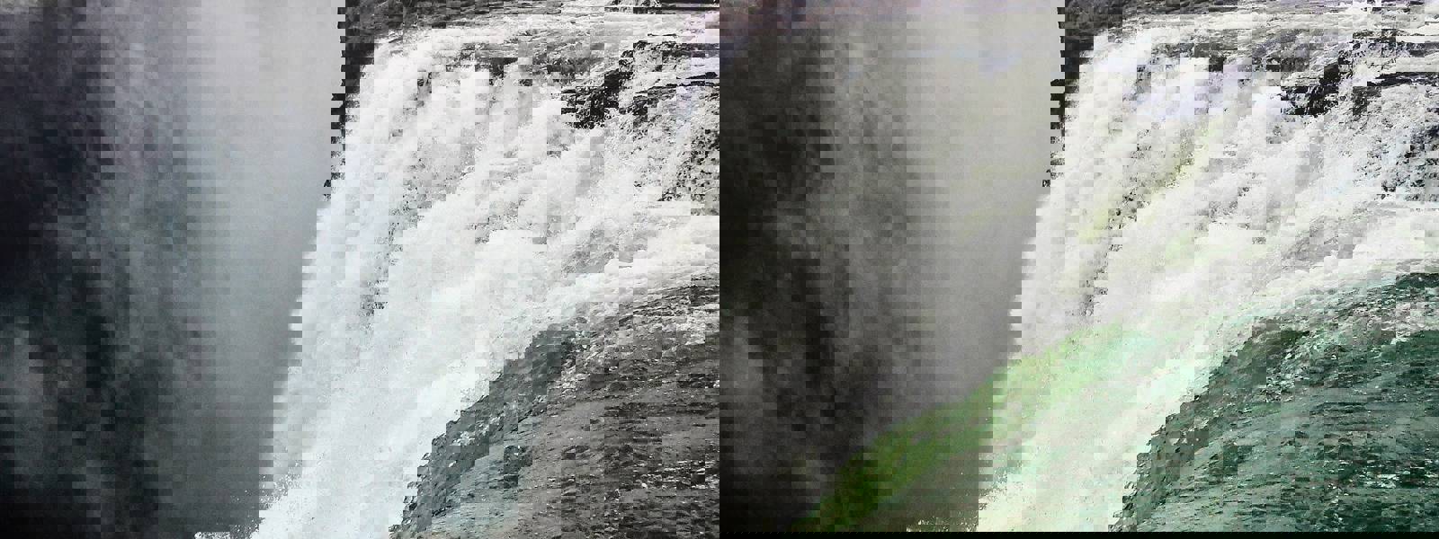 Close-up of a waterfall cascading over a rocky edge into misty surroundings.