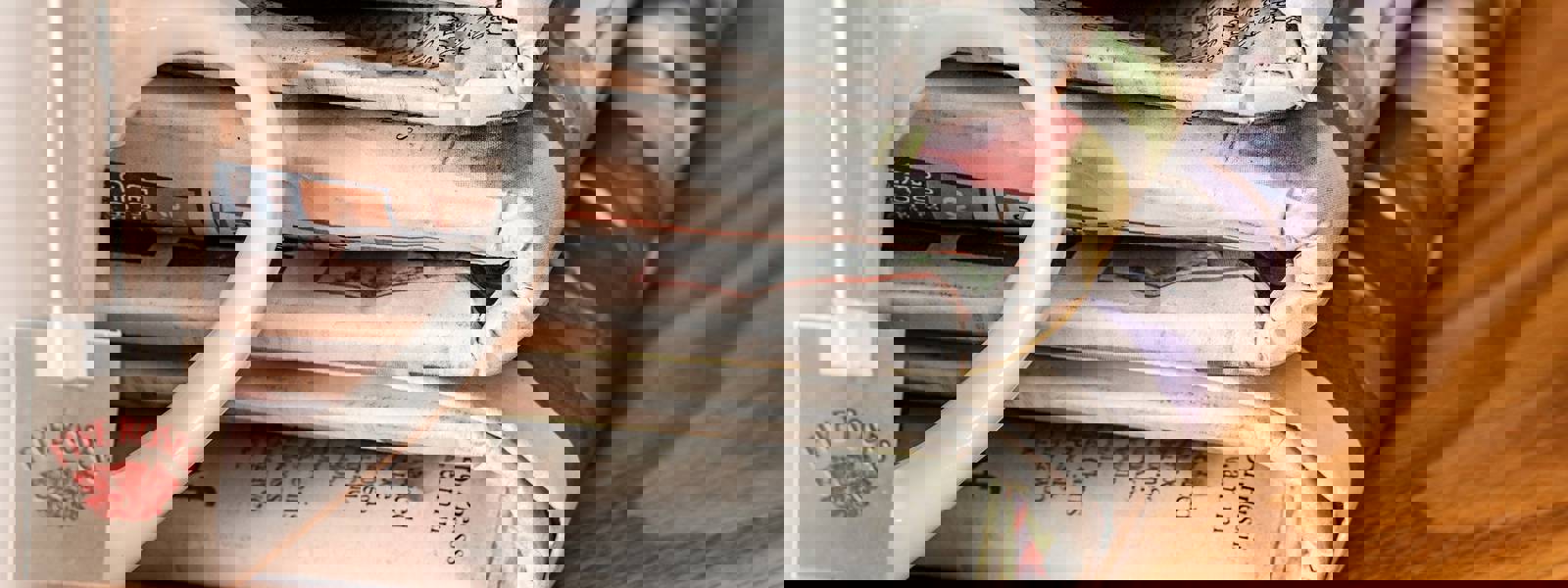 A stack of newspapers beside a cup of tea on a wooden table.