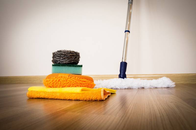 A stack of cleaning cloths and a mop on a wooden floor, ready for cleaning tasks.