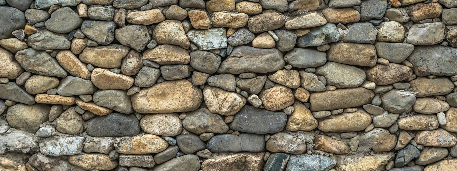 A textured wall made of various sizes of smooth, rounded stones.